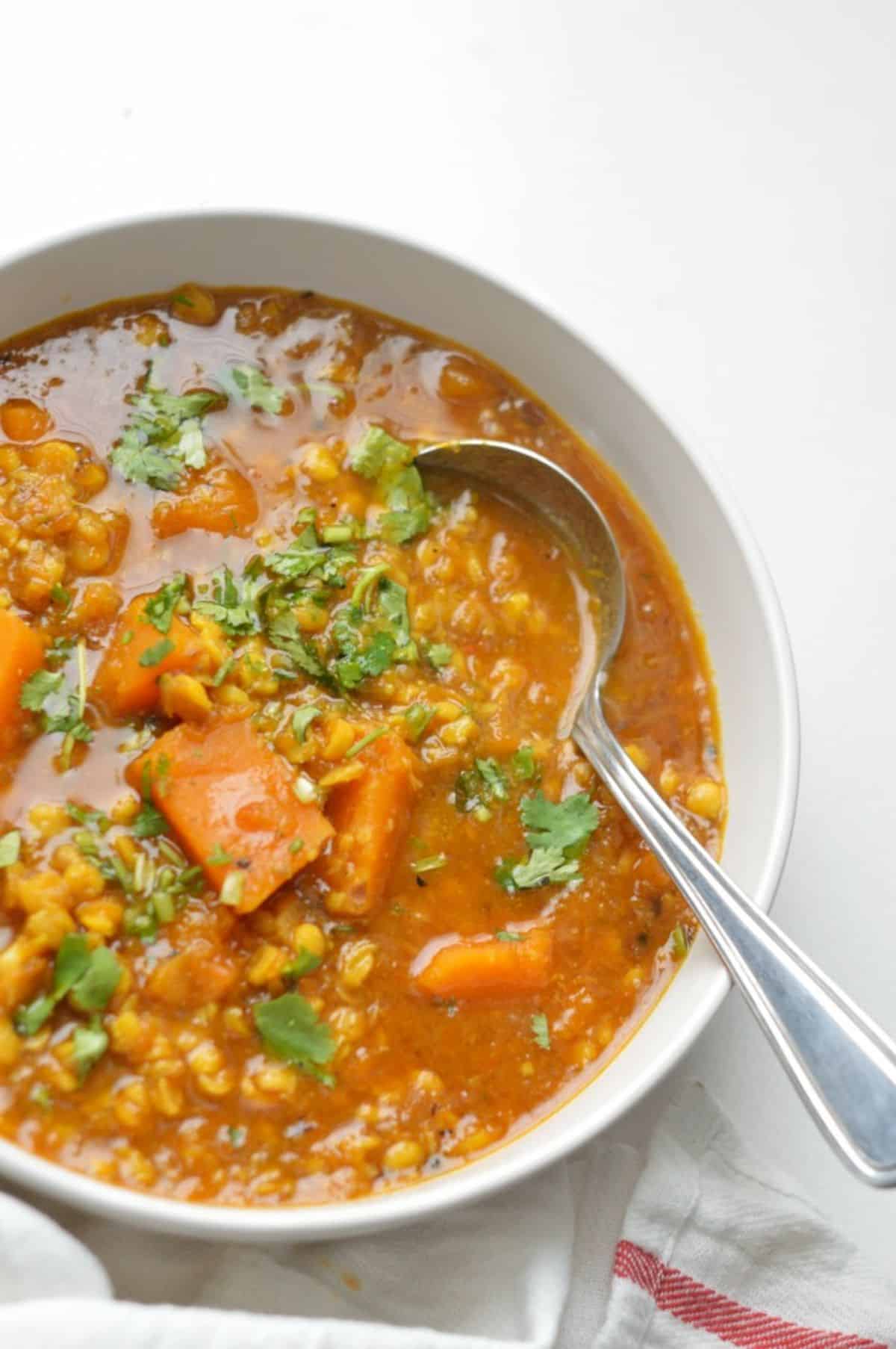 Pumpkin Chana Dal in a white bowl with a spoon.