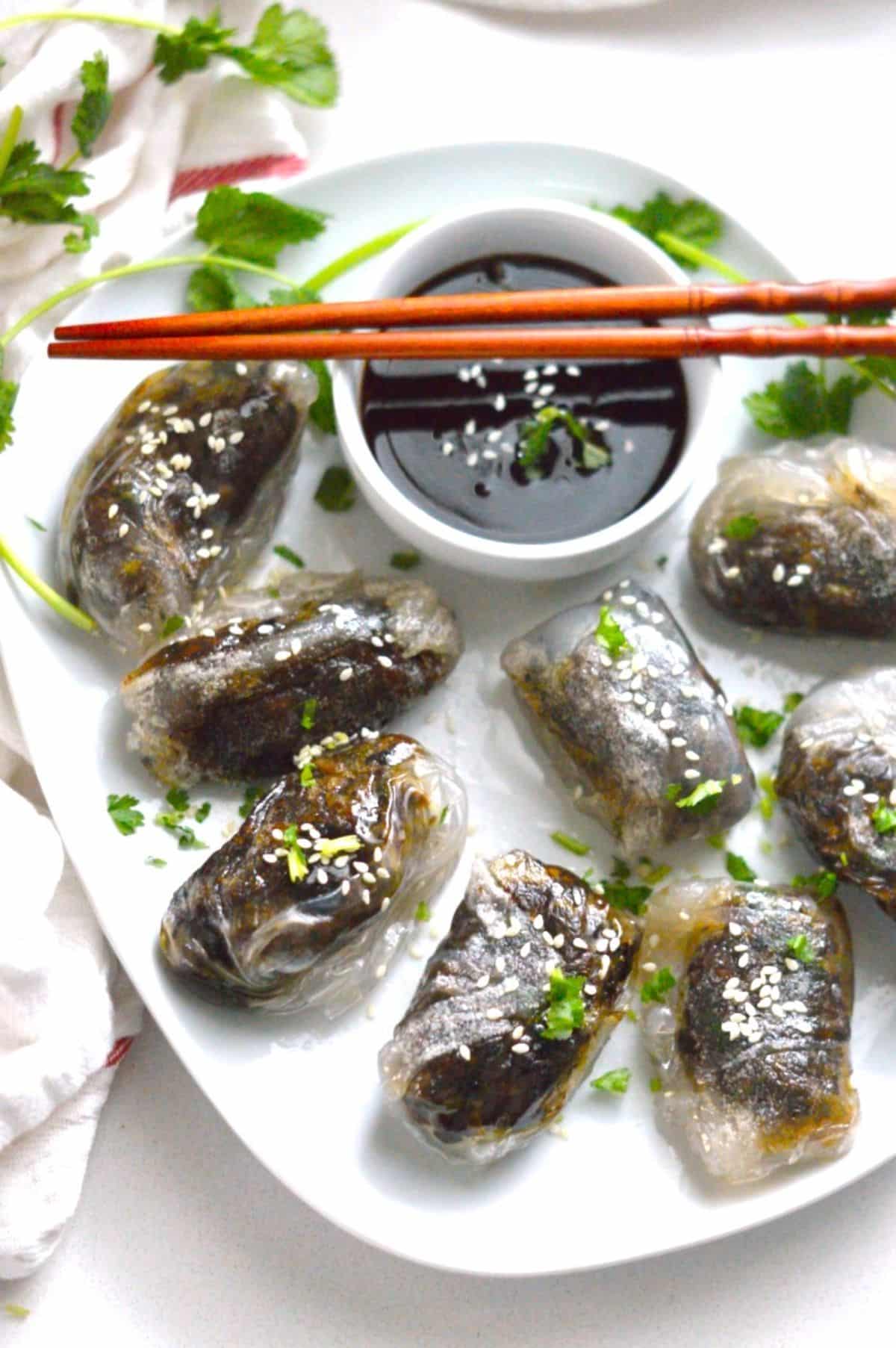 Rice Paper Dumplings on a white tray with a bowl of sauce and chopsticks.