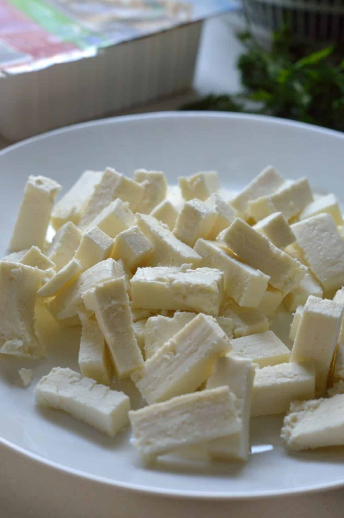 Cubed paneer on a white plate.