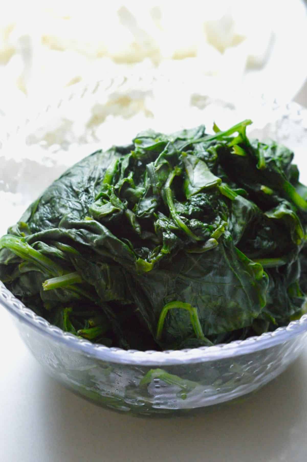 A plastic container full of washed spinach.