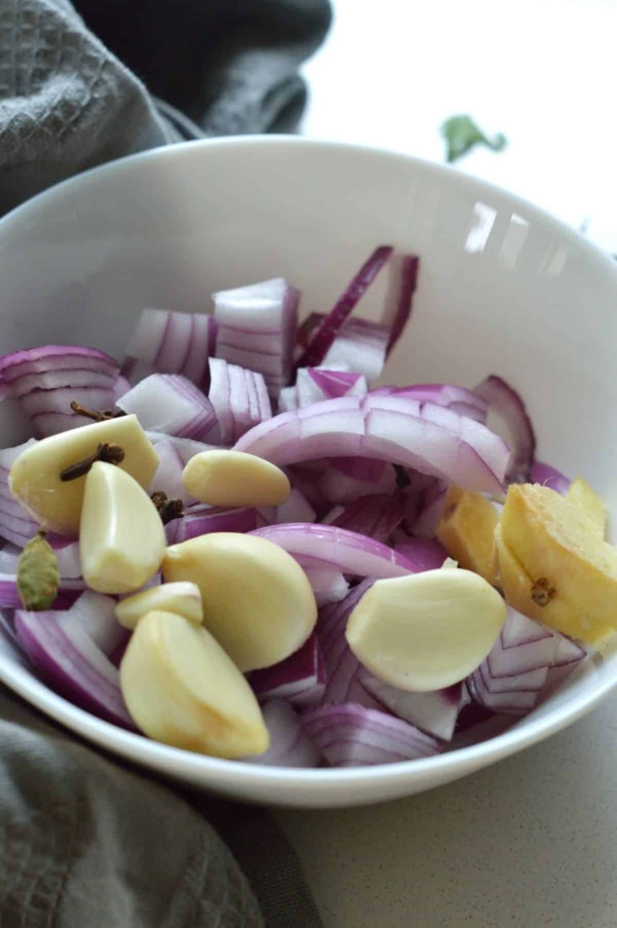 Chopped onions, ginger, garlic in a white bowl.