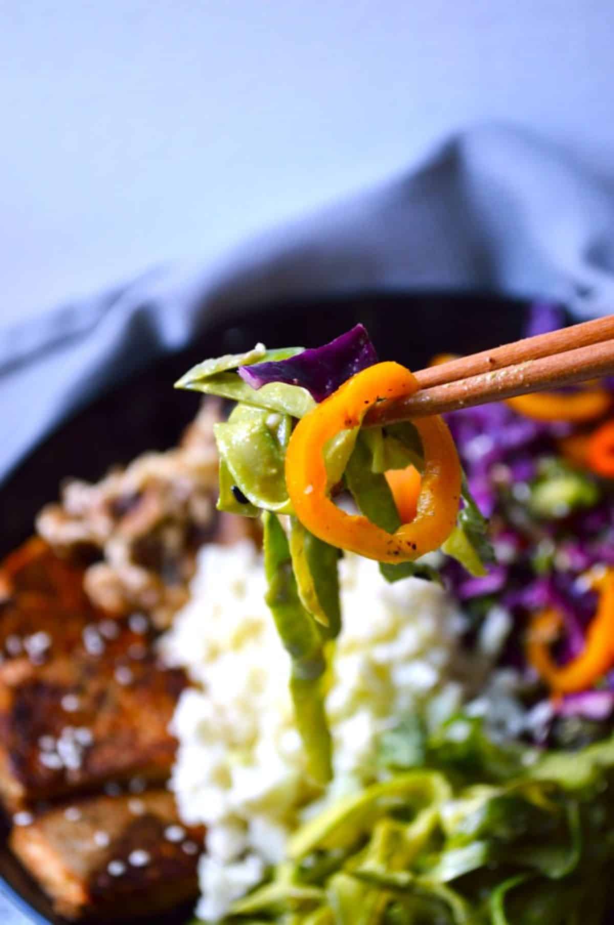 Shaved Asparagus noodles with other veggies on chopsticks.