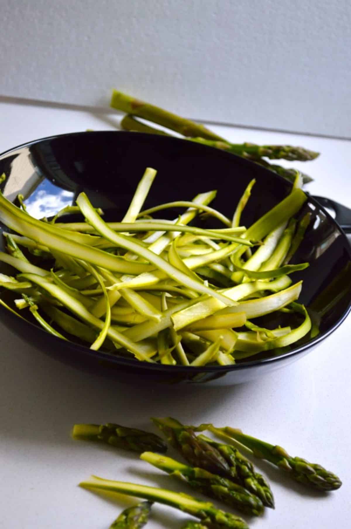 Shaved Asparagus on a black plate.