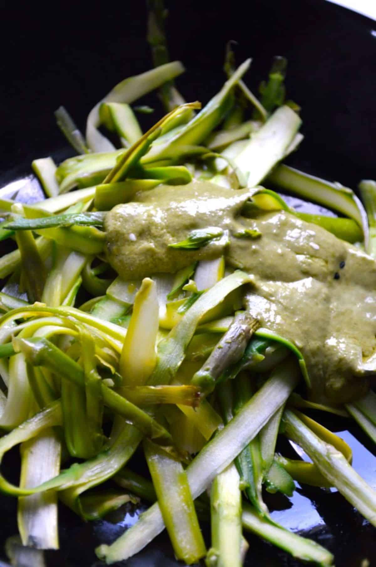 Shaved Asparagus on a black plate with a sauce.