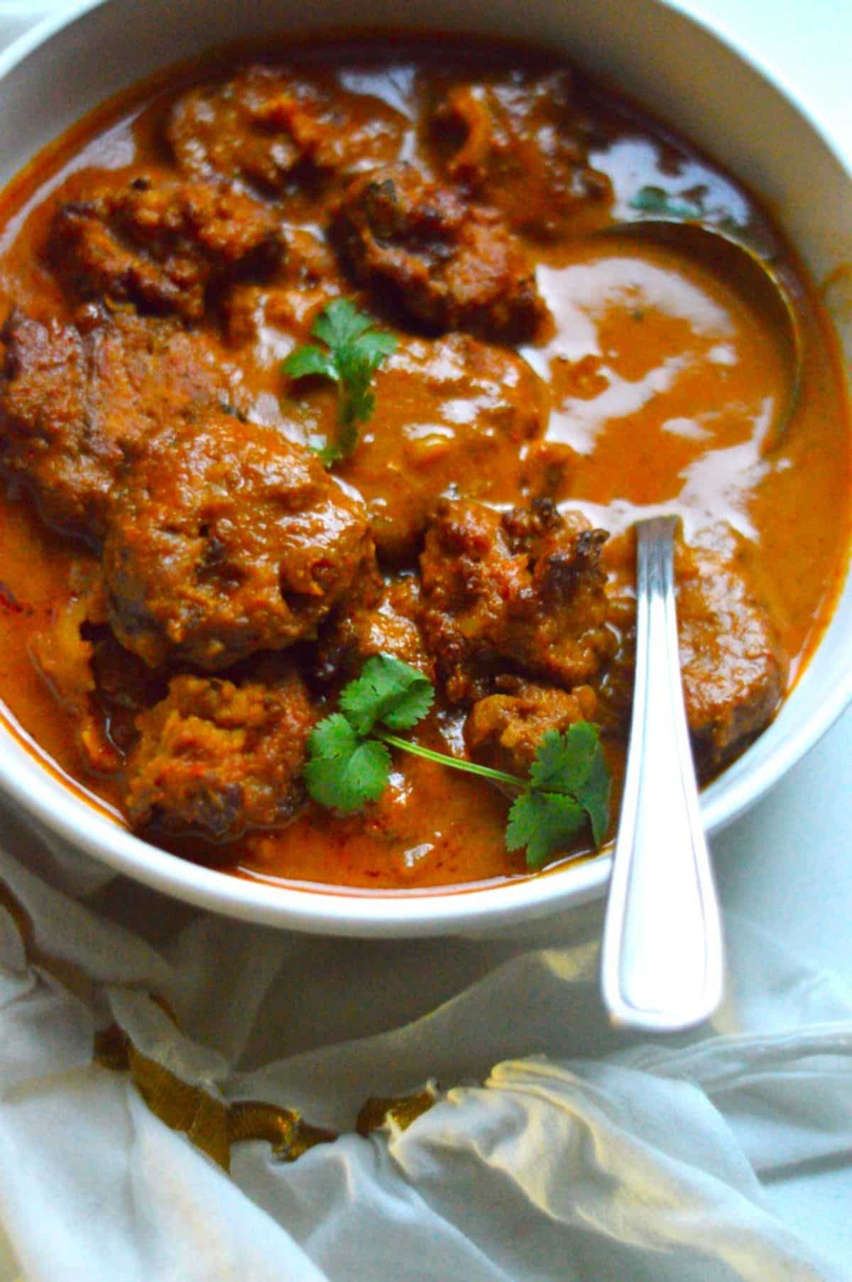 Vada Curry dish in a white bowl with a spoon.