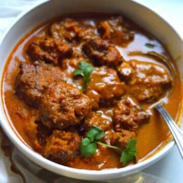 Vada Curry dish in a white bowl with a spoon.