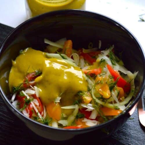 Vegan Green Papaya Salad in a black bowl on a wooden tray.