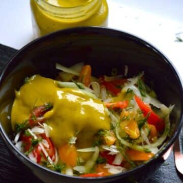 Vegan Green Papaya Salad in a black bowl drizzled with a spicy mango dressing.