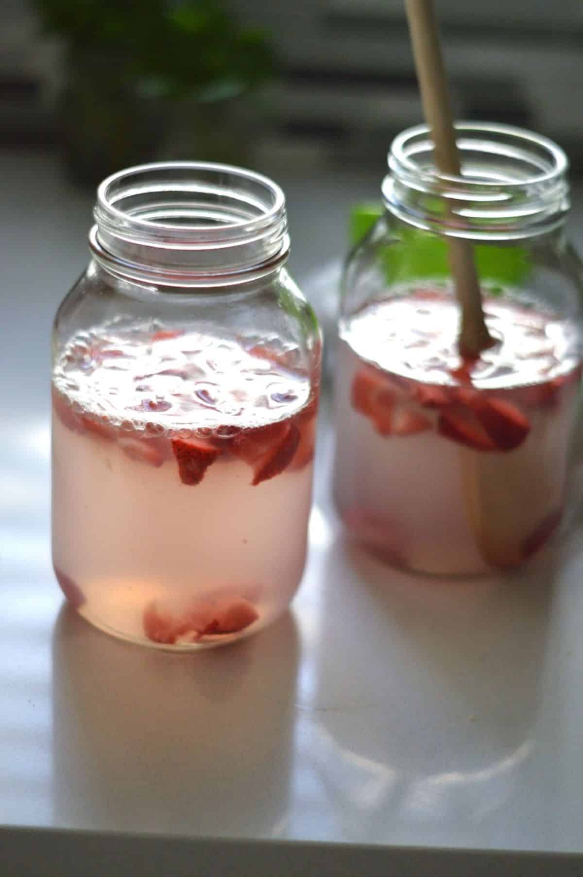 Homemade Water Kefir with fruits in glass jars.