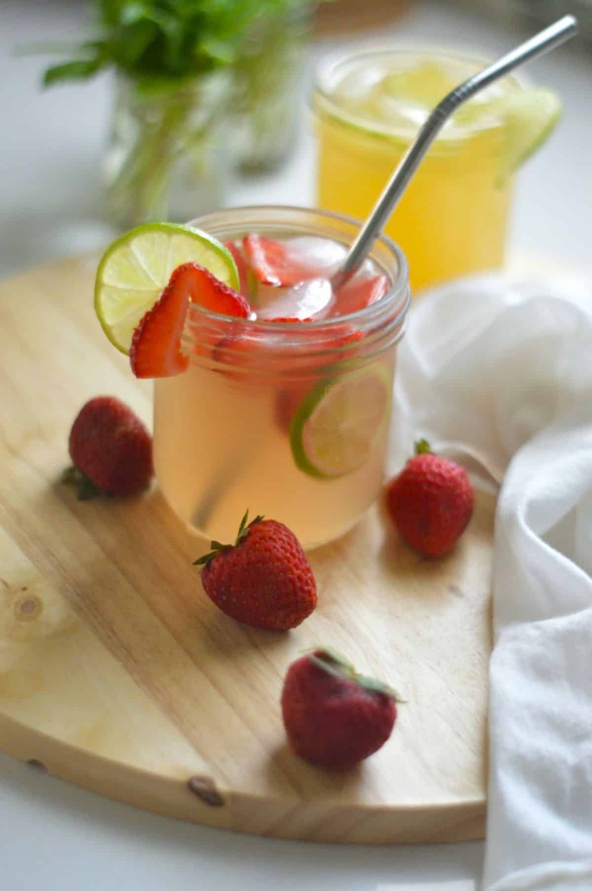 Homemade Water Kefir with fruits and a straw in a glass cup.