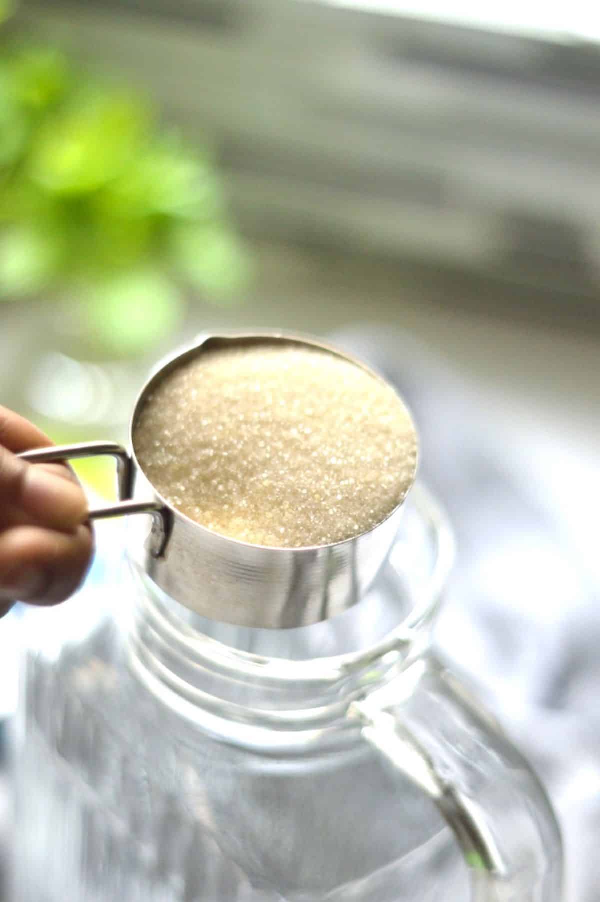 Adding sugar in a glass jar.