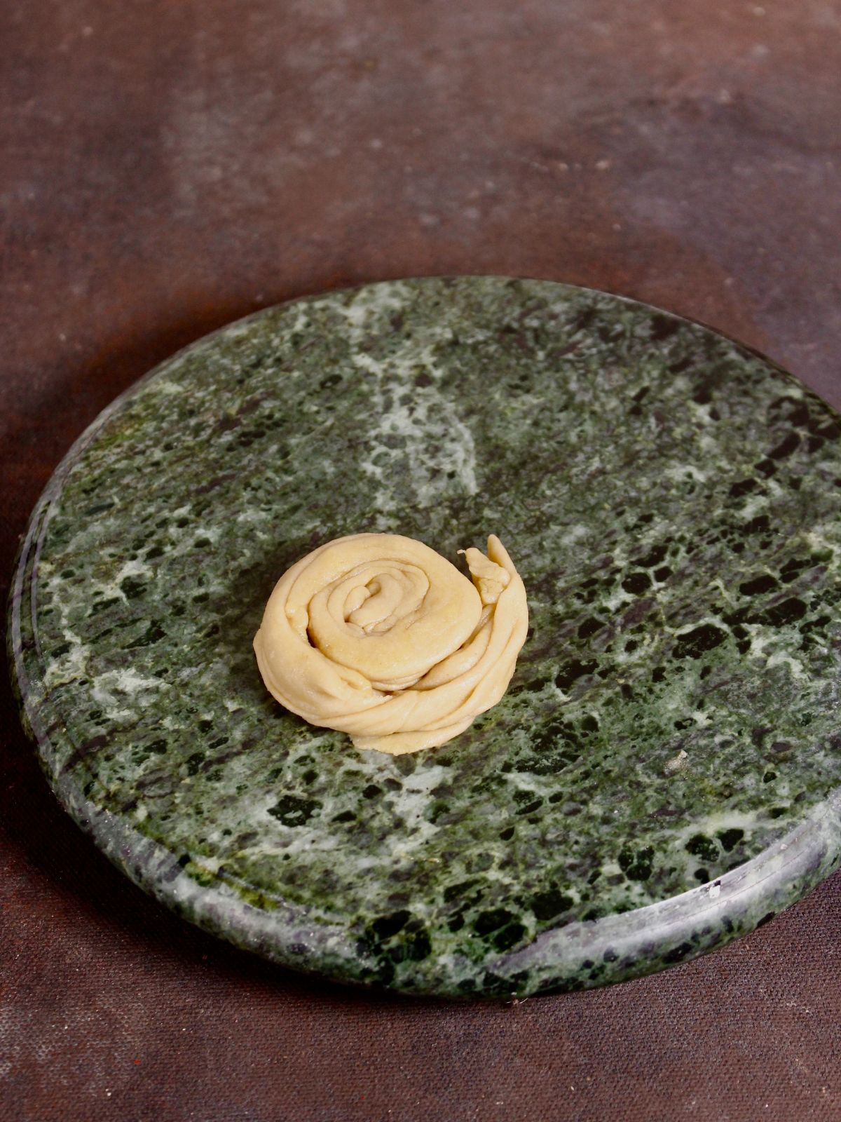 roll the dough rope into the flattened ball and then again make a roti out of it 