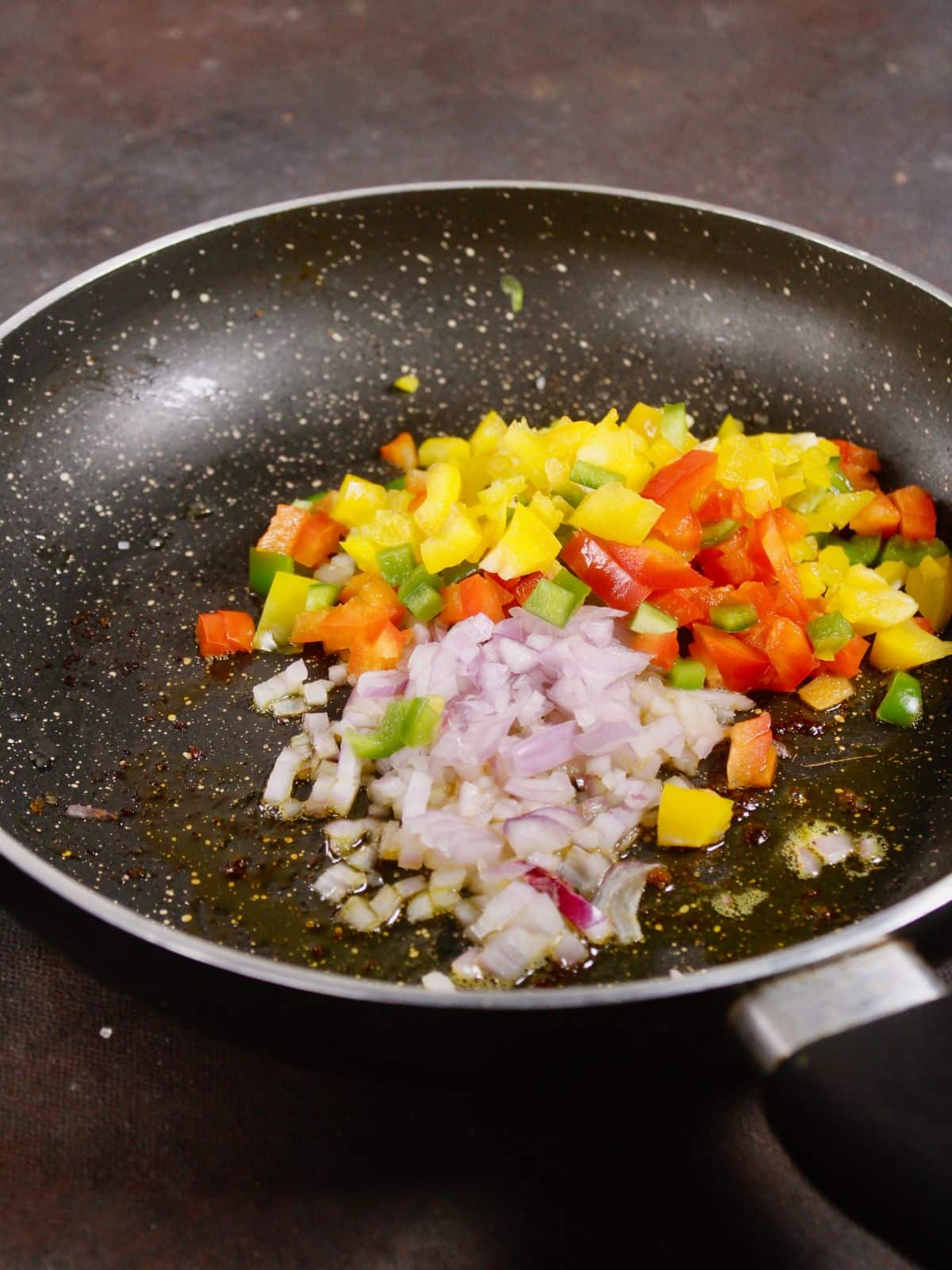 add chopped bell pepper and onions with oil on a pan 
