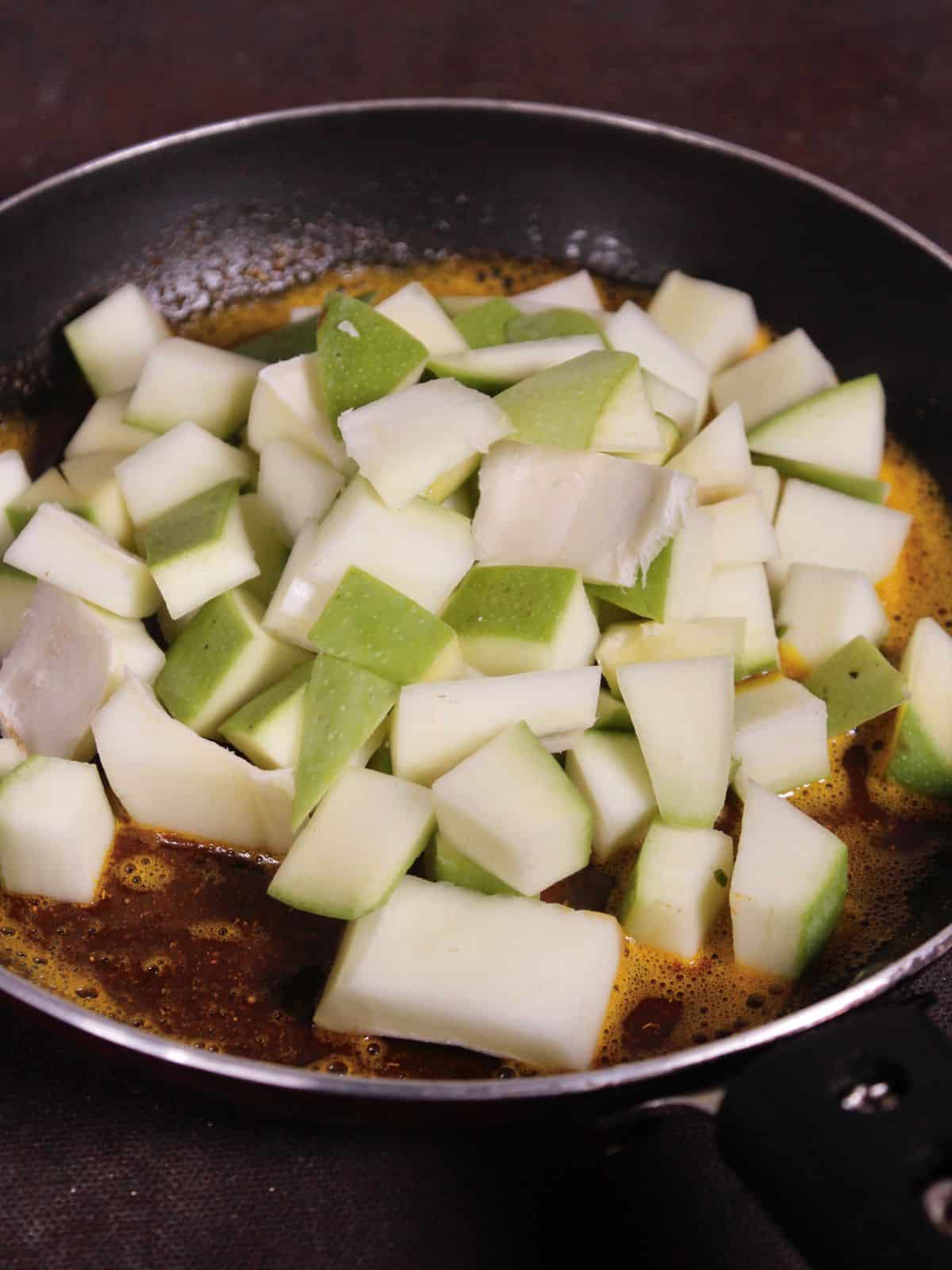 add chopped raw mangoes to the pan and mix well 