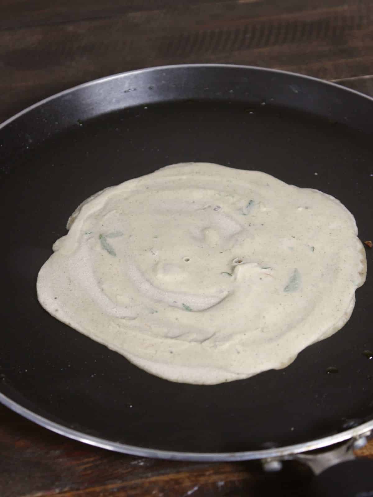 spread the dosa batter on a pan 