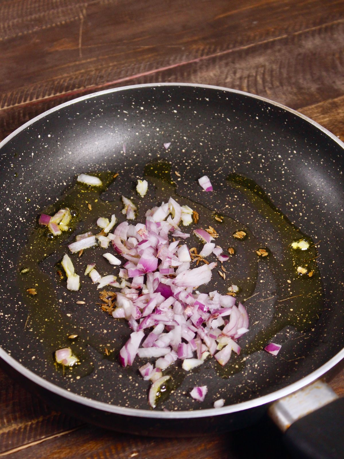 chopped onions with cumin seeds in a pan 