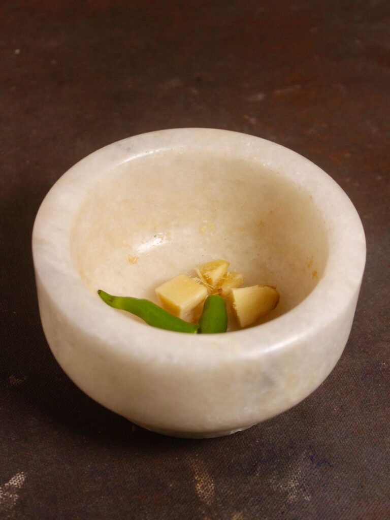 ginger and green chilies in a pestle and make it a paste 