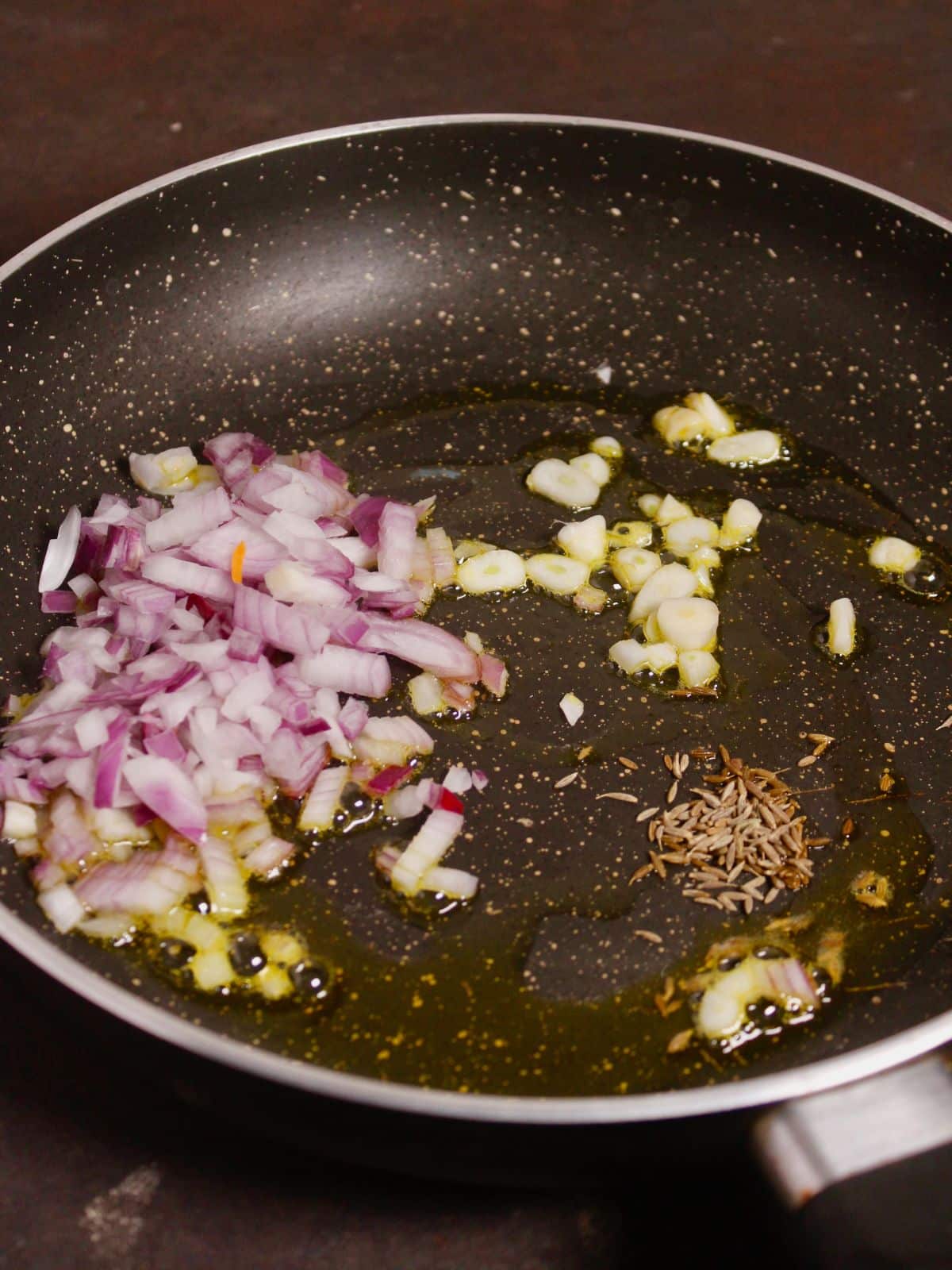 add chopped onions, garlic, and cumin seeds with oil into the pan 