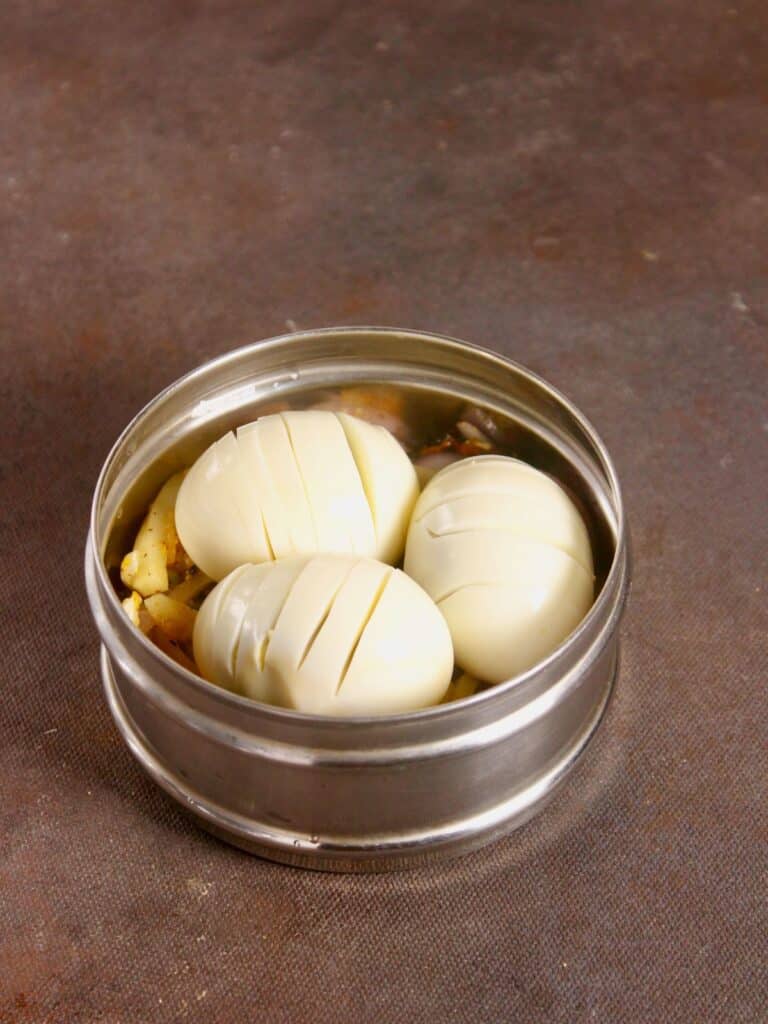take a steel container and add boiled eggs and garnish it with the prepared mix 