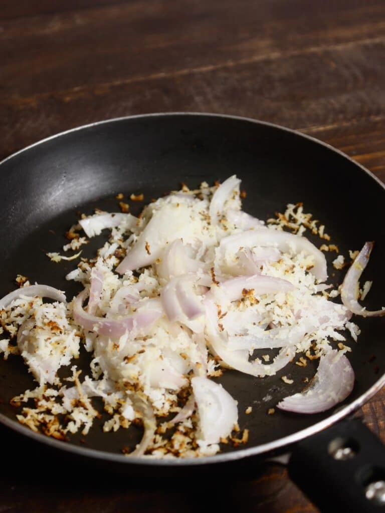 desiccated coconut and sliced onions in a pan 